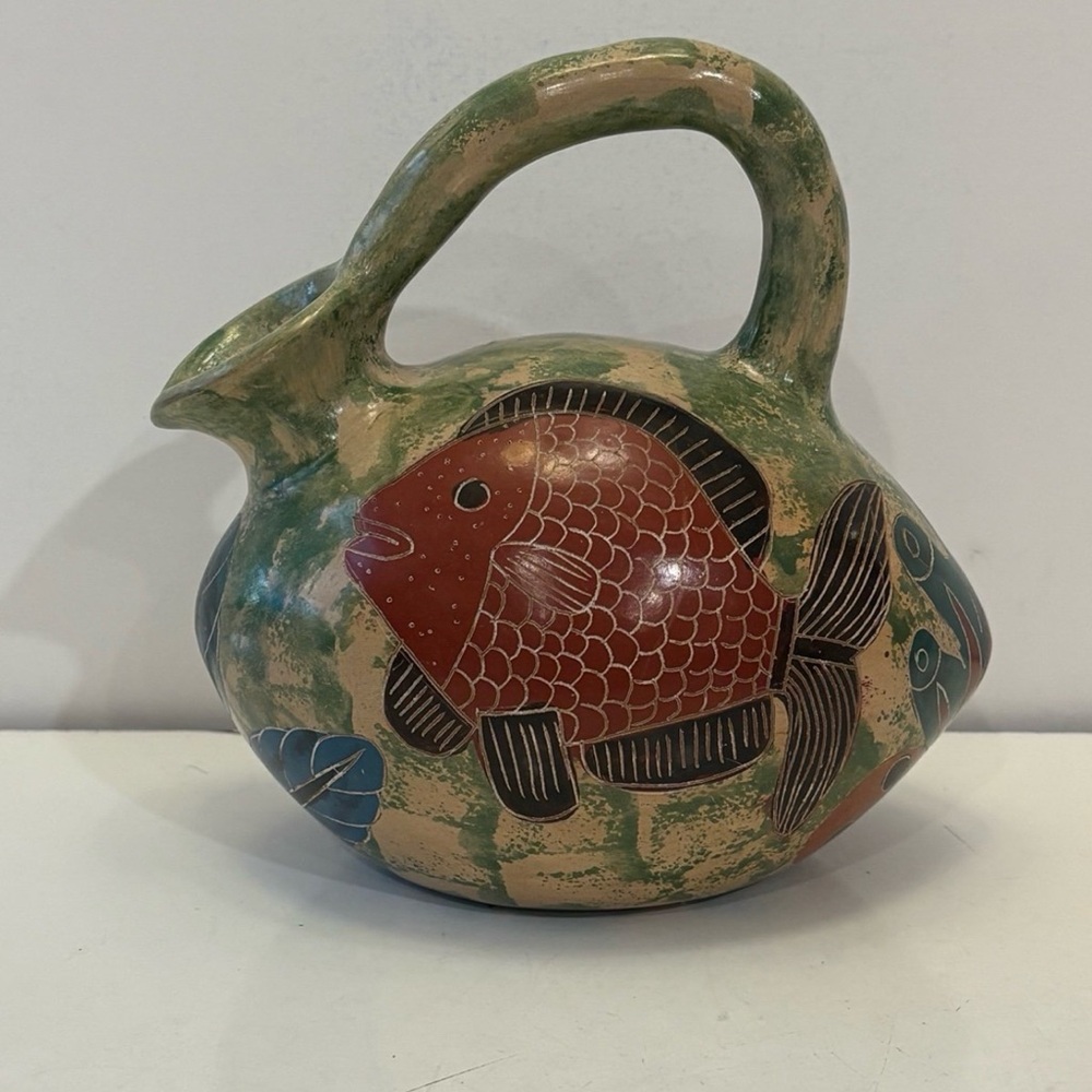 Handmade pottery pitcher with a fish on it
